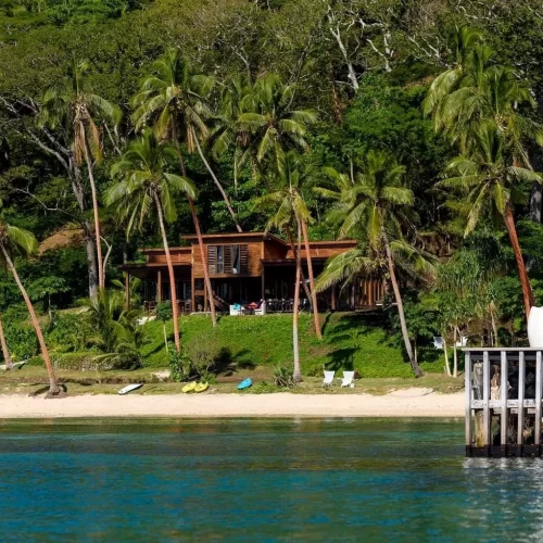 large green palm tree forest with a hidden resort on the beach with clear blue waters