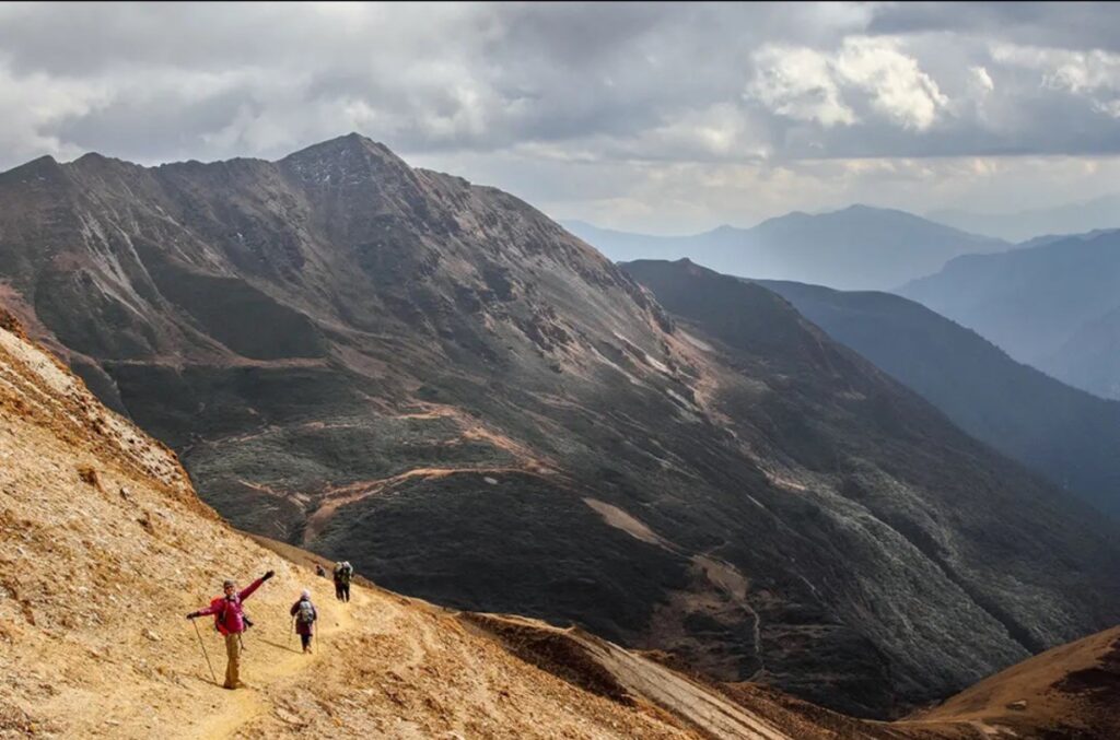 Hiker walking along the Trans Bhutan Trail with a view of Himalayan mountains