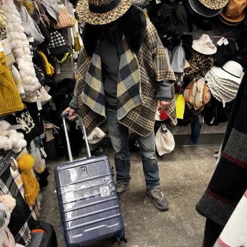 Packing in a thrift shop with a suitcase and many clothes. The definitive packing guide for a sabbatical abroad.
