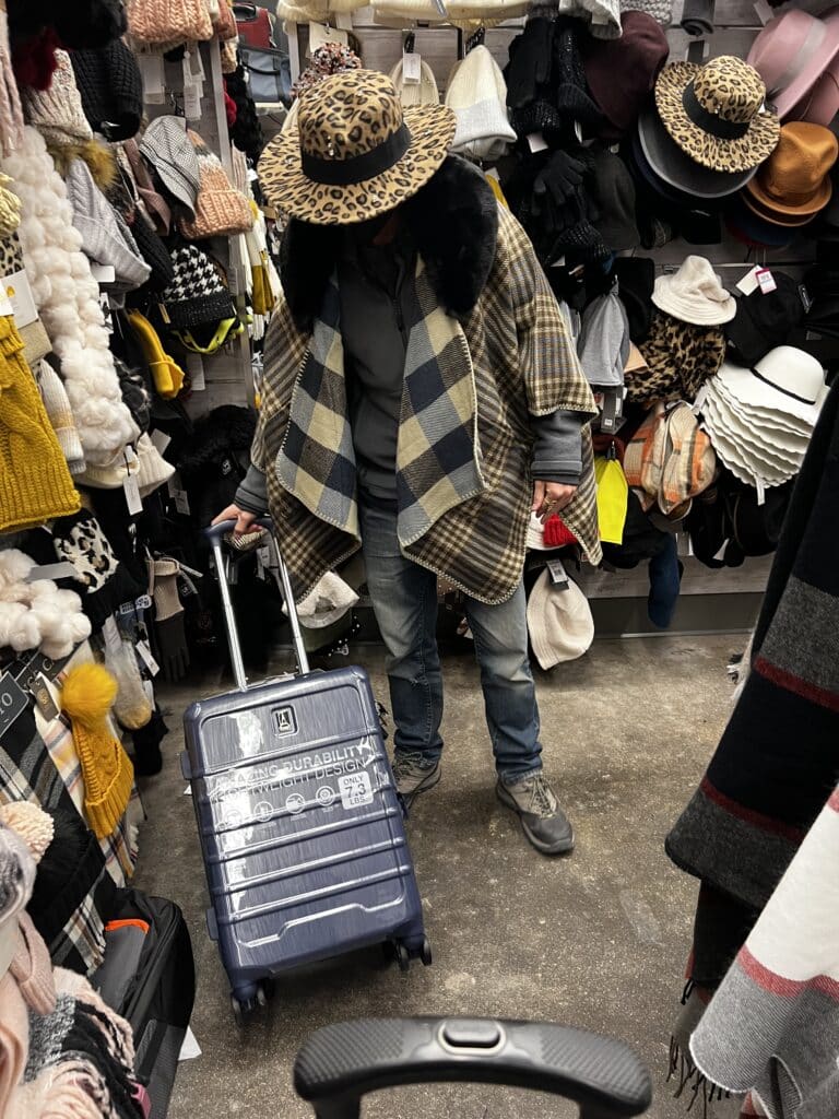 Packing in a thrift shop with a suitcase and many clothes. The definitive packing guide for a sabbatical abroad.