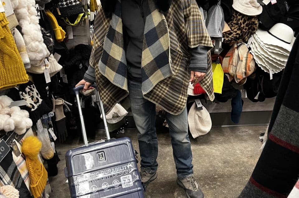 Packing in a thrift shop with a suitcase and many clothes. The definitive packing guide for a sabbatical abroad.